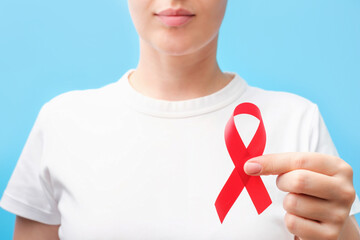 Young woman in white t-shirt holding a red ribbon close-up.