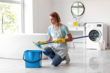 Young housewife with mop in bathroom