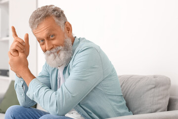 Senior bearded man sitting on sofa at home