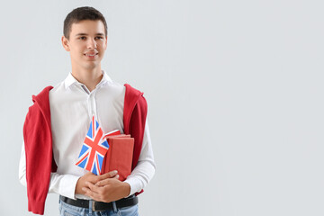 Teenage boy with UK flag and books on light background