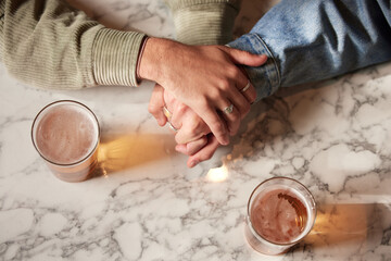 Couple holding hands, above glass beer and bar with comfort, support or bonding together with...