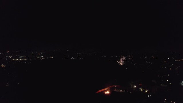 Footage of a English November the 5th Bonfire night in the United Kingdom. Dark cold and wet, showing street lights cars houses and fireworks. Drone footage