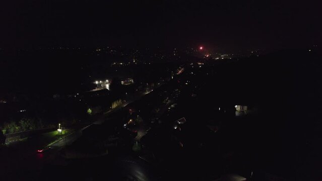 Aerial view footage of a typical November the 5th Bonfire night in the United Kingdom. Dark cold and wet, showing street lights cars houses and fireworks. Drone footage