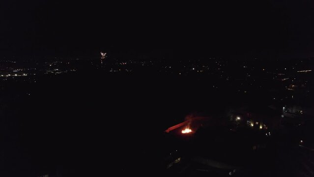 Footage of  November the 5th Bonfire night in the United Kingdom. Dark cold and wet, showing street lights cars houses and fireworks. Drone footage