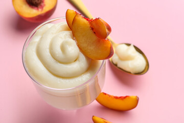 Glass of tasty vanilla pudding with peach on pink background, closeup
