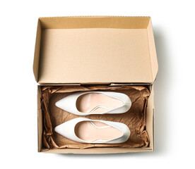 Cardboard box with high-heeled shoes on white background