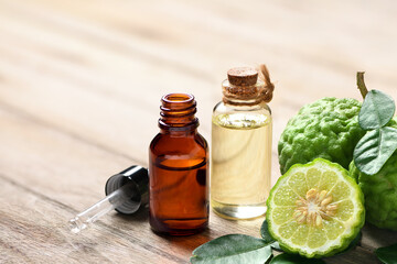 Bergamot essential oil with half cut and leaves on wooden table.