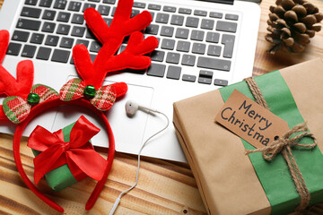 Laptop, Christmas gifts, earphones and reindeer horns on wooden background, closeup