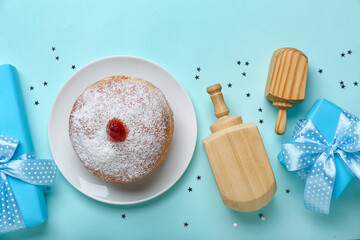 Plate with tasty doughnut, dreidels and gifts for Hanukkah celebration on blue background