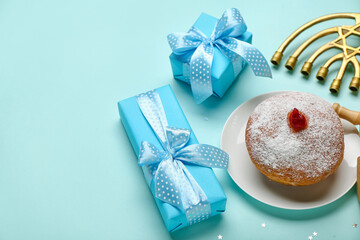 Plate with tasty doughnut, menorah and gifts for Hanukkah celebration on blue background