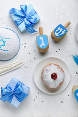 Plate with doughnut, dreidels and gifts for Hanukkah celebration on white background