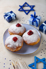 Plate of tasty donuts for Hanukkah celebration, gifts and decor on light background