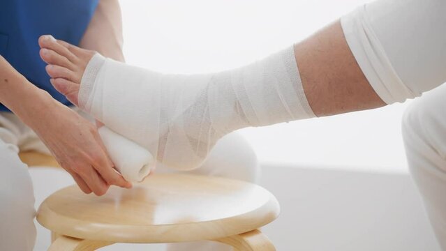 医者に包帯を巻かれる中年男性　医療イメージ