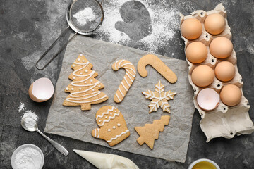 Sheet of baking paper with tasty Christmas cookies and ingredients on grunge background