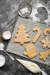 Sheet of baking paper with tasty Christmas cookies and cream on grunge background