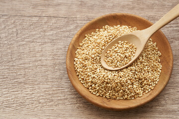roasted sesame seed in wood and spoon plate on wooden table background. a pile of  Toast sesame...