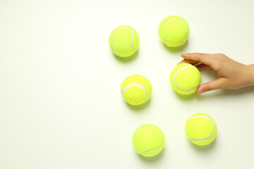 Flat lay with tennis balls and female hand on white background