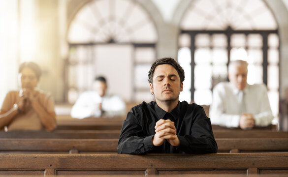 Prayer, Religious And Young Man In Church With Congregation, Faithful And Hands Together. Religion, Male And Worship In Tabernacle For Guidance, Spiritual And Support With Closed Eyes And Praying