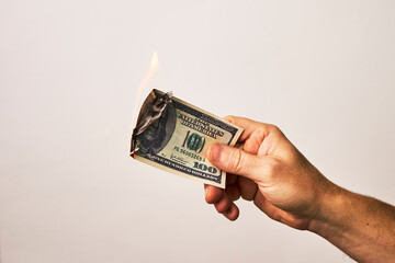 Male hand holding burning dollar money on white background