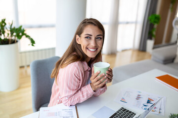 Young business women in the office drinking coffe and looking through a window
