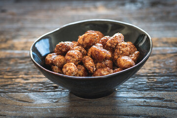 Homemade sweet caramelized almonds in a little cermaic bowl on a dark wooden rustic table