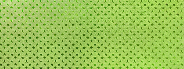 Light green christmas background from metal foil paper with a pattern of sparkling stars, macro....