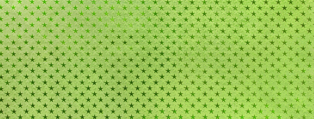 Light green christmas background from metal foil paper with a pattern of sparkling stars, macro. Olive backdrop.