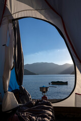 Ouverture d'une tente de camping sur un paysage de lac entouré de montagnes à l'automne au...