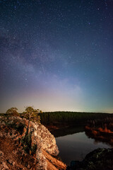 Milky way and stars in the night sky above the rocky cliff and Chusovaya river