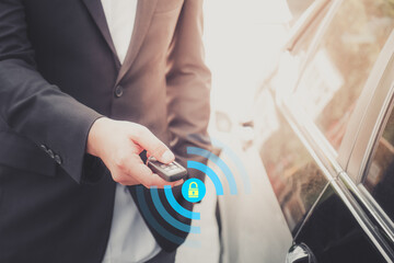 The businessman opening his luxurious car door with a modern remote control key. The young man executive is locking the automobile with the security system. Keyless in male hand with copy space.