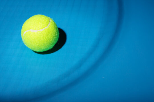tennis ball in the shadow of a racket on a blue background