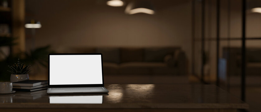 Modern workspace with laptop mockup and copy space over blurred dark living room