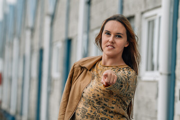 happy woman with leather jacket in autumn on the street pointing a direction