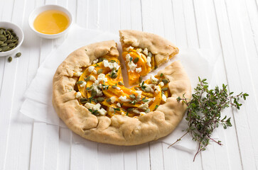 Homemade galette with pumpkin, feta cheese, honey, pumpkin seeds and thyme on white background