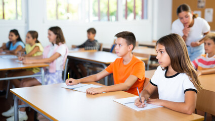 Obraz premium Boy and girl sitting at desk in classroom and studying during lesson in school.