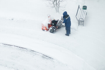 janitor cleans the street from snow,worker removes snow with a machine