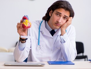 Young doctor cardiologist with heart model