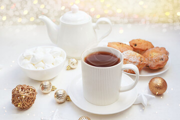  Winter, Christmas, New Year decoration composition, concept, background. White Mug, cup of hot tea, coffee, meringue, knitted plaid. Christmas lights. Christmas mood morning. Xmas greeting card. 