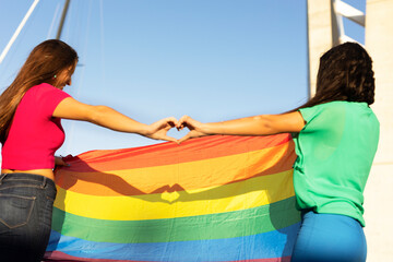 Obraz premium Happy couple of lesbian ladies making a heart sign with their hands