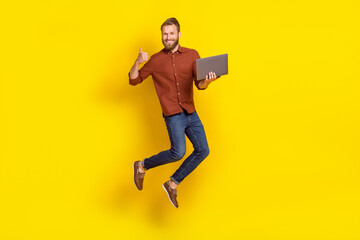 Fototapeta na wymiar Full body portrait of handsome guy jumping hold netbook show thumb up feedback isolated on yellow color background