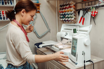 A woman tailor makes embroidery on an embroidery machine in a home workshop.Mending clothes...