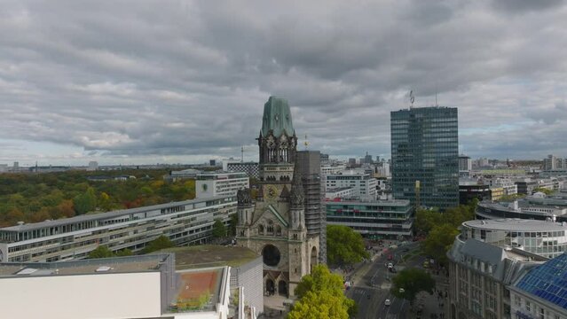 Pull back footage of ruin of old church as reminder of World War II. Modern buildings around. Charlottenburg neighbourhood, Berlin, Germany