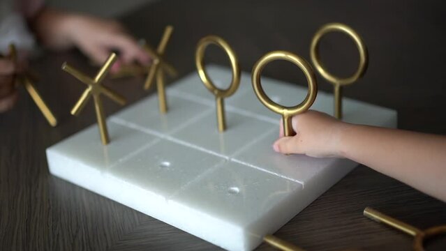 Children play tic-tac-toe made of metal and stone