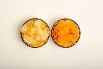 Paprika flavored potato chips and original chips with salt in small glass bowls, two kind of sauces from above on a light beige background. Snacks for group of people.