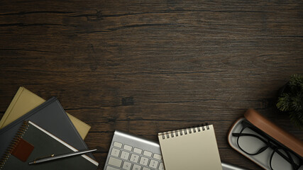 Top view of eyeglasses, keyboard, pen and notepad on wooden working desk. Simple workplace