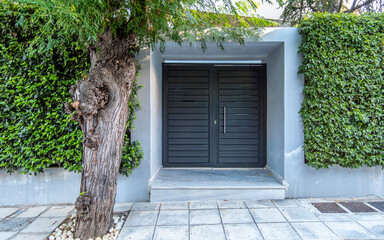 A contemporary house entrance, with a grey painted solid iron door by the sidewalk. Athens, Greece.