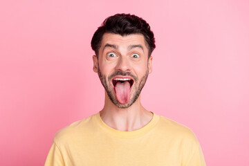 Photo of good mood funky guy with brunet hairstyle dressed yellow t-shirt stick out tongue fooling...