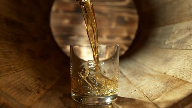 Super Slow Motion Shot of Pouring Whiskey into Glass inside Wooden Barrel at 1000fps.