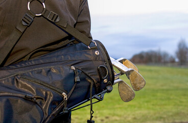 Golfclubs in black bag on back of golfer