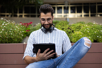 Obraz premium Handsome man checking his tablet sitting on a bench